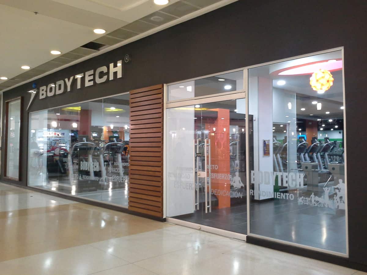 A mujer se le cayó encima un espejo en gimnasio de Bogotá En un gimnasio Bodytech ubicado en el centro comercial Centro Mayor una joven sufrió un accidente. Según la denuncia que realizó a un medio de comunicación, cuando estaba haciendo su rutina de ejercicio un espejo se le cayó encima lesionándola de gravedad.