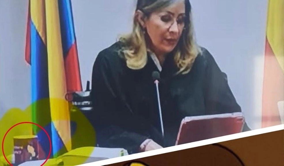 Pocillo de la jueza llama la atención durante fallo en juicio de Álvaro Uribe La jueza que dictó el fallo aparece concentrada en la lectura del documento, mientras detrás ondean las banderas de Colombia y Antioquia.